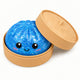 Blue glittery ball with a smiling face in a tan container on a white background